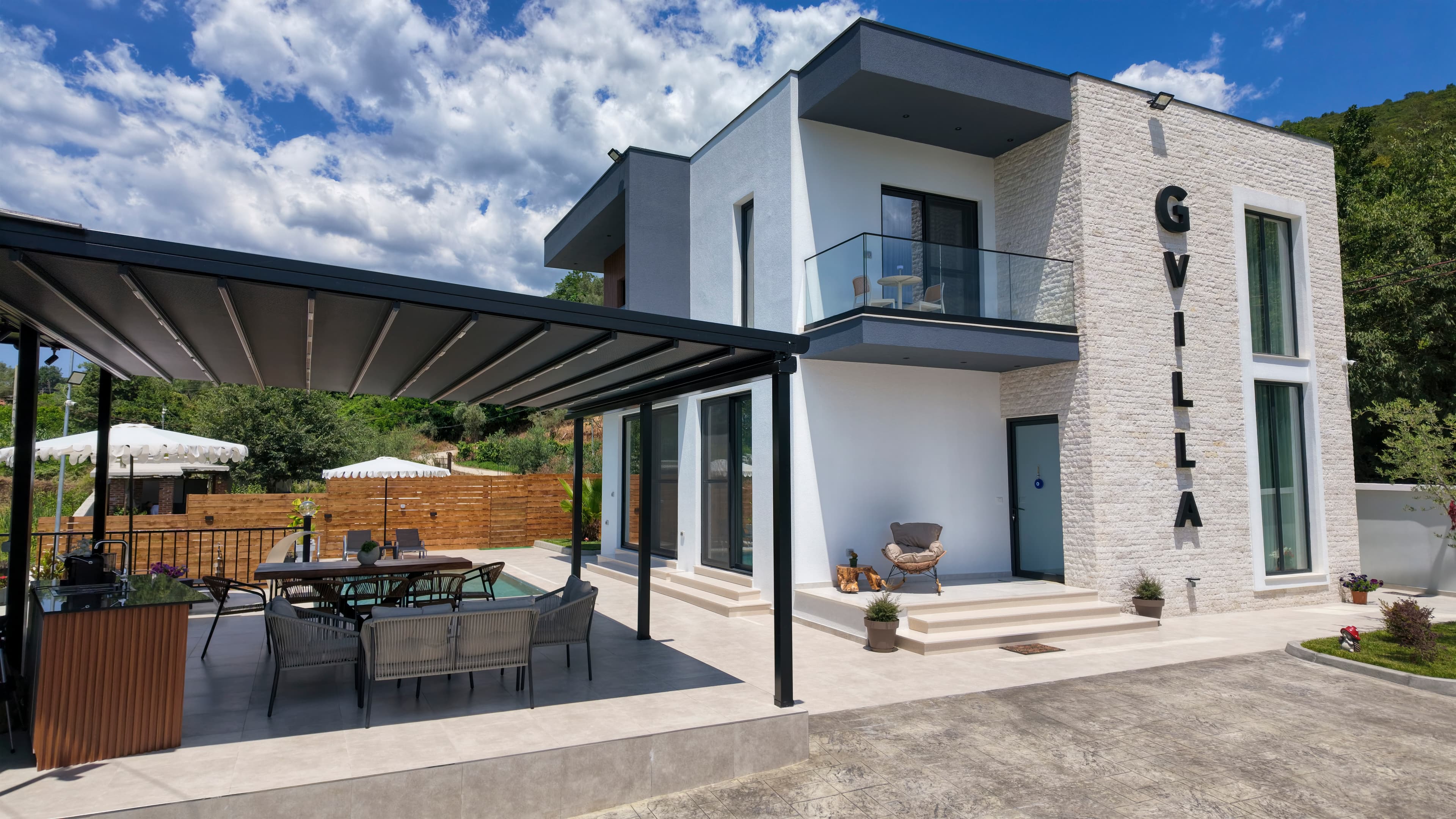 The front of G Villa, its covered terrace and the hills behind